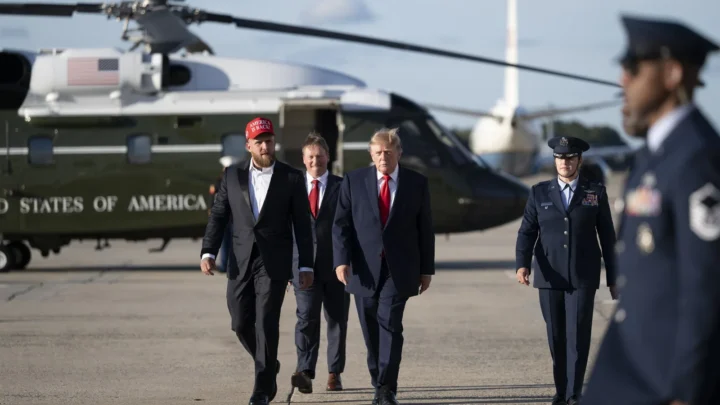 Jake Paul, de boné vermelho, caminha ao lado do presidente Donald Trump na Base Conjunta Andrews, em Maryland, antes de embarcar no Air Force One rumo a Youngstown, Ohio, em 12 de outubro de 2026
