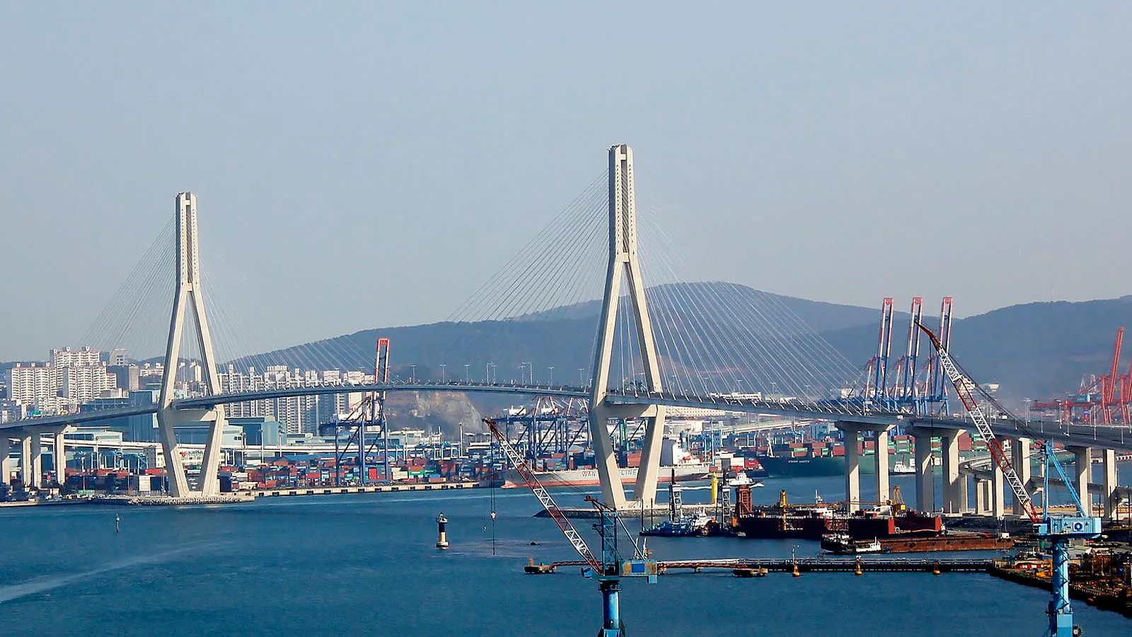 Ponte estaiada Busanhang sobre o porto de Busan, com guindastes de contêineres e a cidade ao fundo, em 2015 (imagem de arquivo)