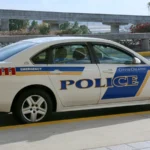 Viatura branca da polícia da cidade de Orlando, com faixas azuis e a palavra "Police" na porta, estacionada junto a um viaduto