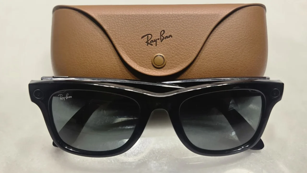 Óculos inteligentes Ray-Ban Meta de primeira geração, de armação preta, apoiados diante do estojo de couro marrom com a marca Ray-Ban (imagem ilustrativa)
