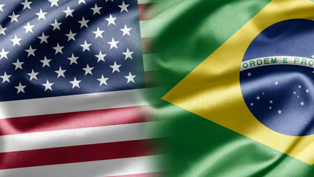 Bandeiras dos Estados Unidos e do Brasil lado a lado, com tecido ondulado e a inscrição "Ordem e Progresso" visível na bandeira brasileira