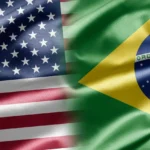 Bandeiras dos Estados Unidos e do Brasil lado a lado, com tecido ondulado e a inscrição "Ordem e Progresso" visível na bandeira brasileira
