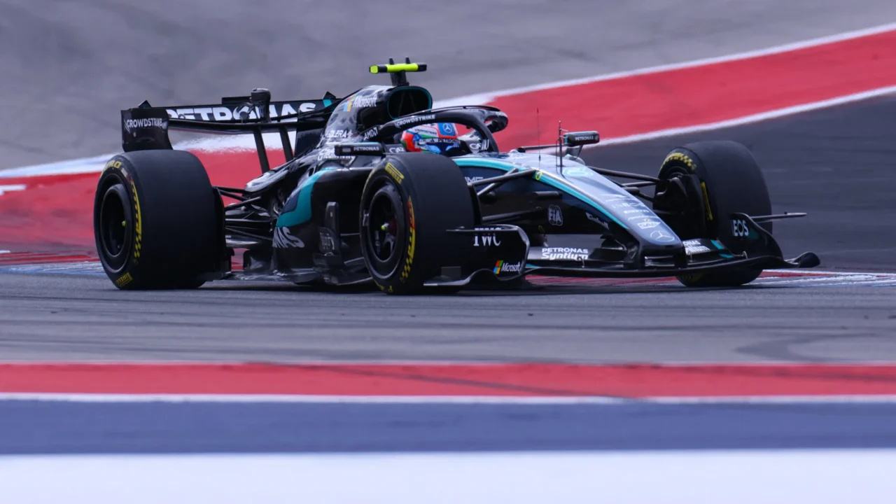 Carro preto e verde da Mercedes com pneus Pirelli em curva na pista de Austin, com patrocínios da Petronas e da Microsoft visíveis na carroceria
