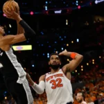 Jogador de camisa preta do San Antonio Spurs arremessa sob marcação do defensor do New York Knicks, o número 32, em jogo de basquete na NBA