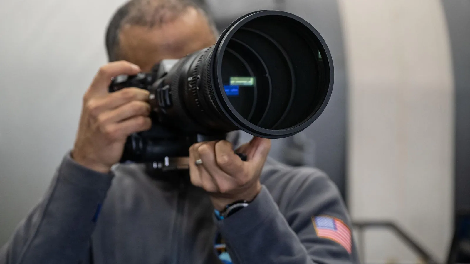 O astronauta Anil Menon aponta uma câmera com lente grande durante treinamento de fotografia no Centro Espacial Johnson, em Houston, em dezembro de 2025