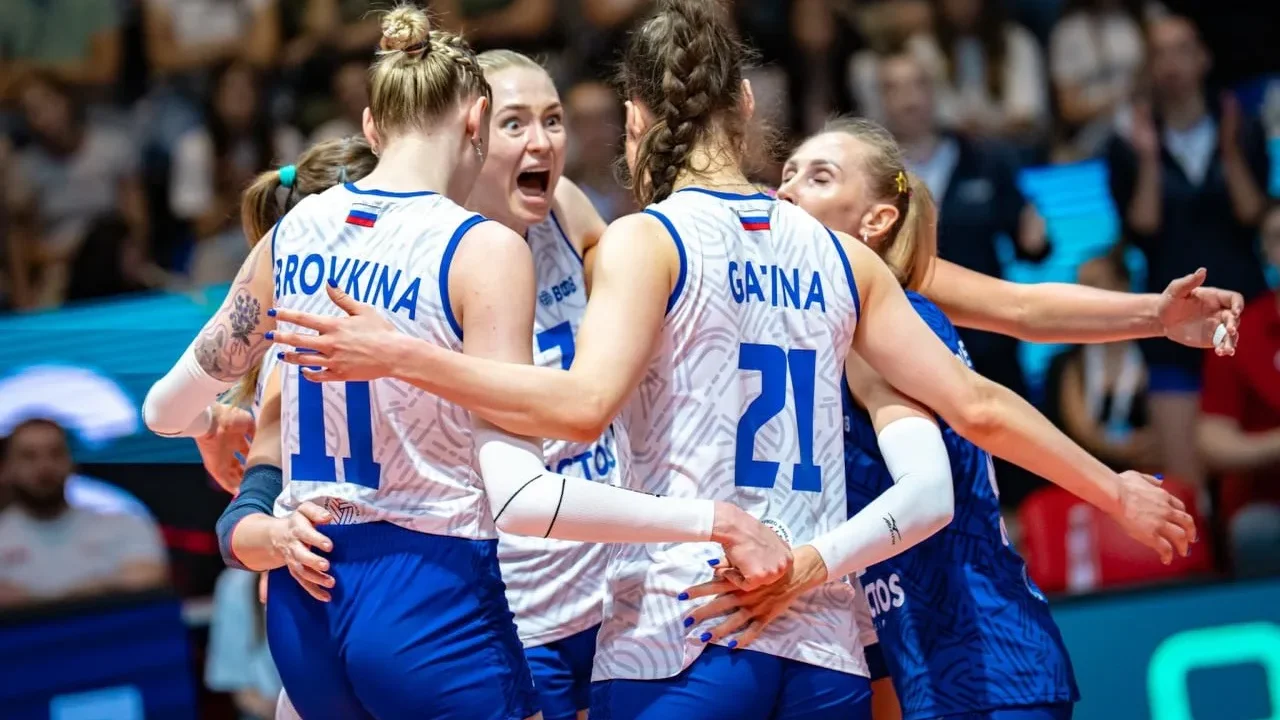 Voleibolistas da Rússia comemoram durante partida, com jogadoras abraçadas na quadra enquanto público assiste ao fundo