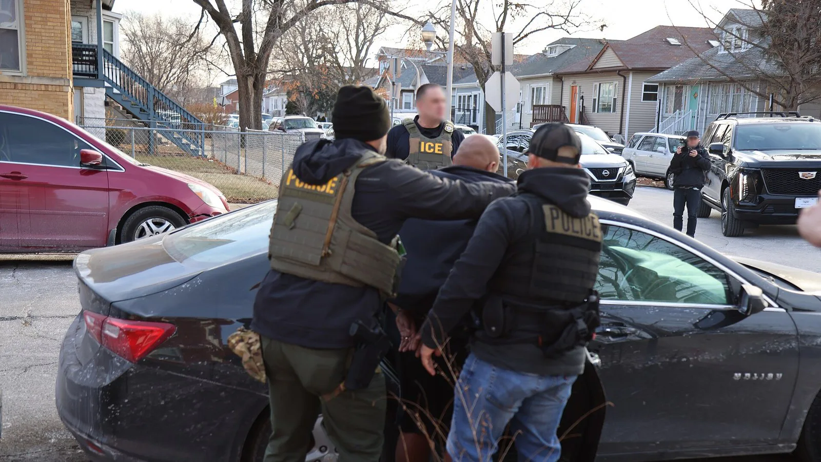 Agentes do ICE com coletes de identificação conduzem um homem até um carro numa rua de Chicago, em operação de 26 de janeiro de 2025 (imagem de arquivo; não é a prisão de Khalil)