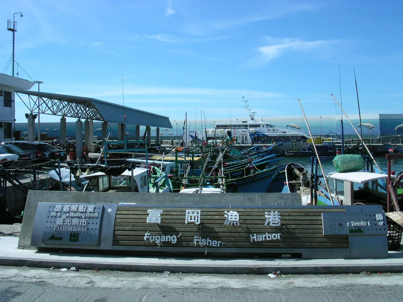 Placa do porto pesqueiro de Fugang, em Taitung, com barcos de pesca atracados e uma balsa ao fundo, em foto de 2005, anos antes do tufão