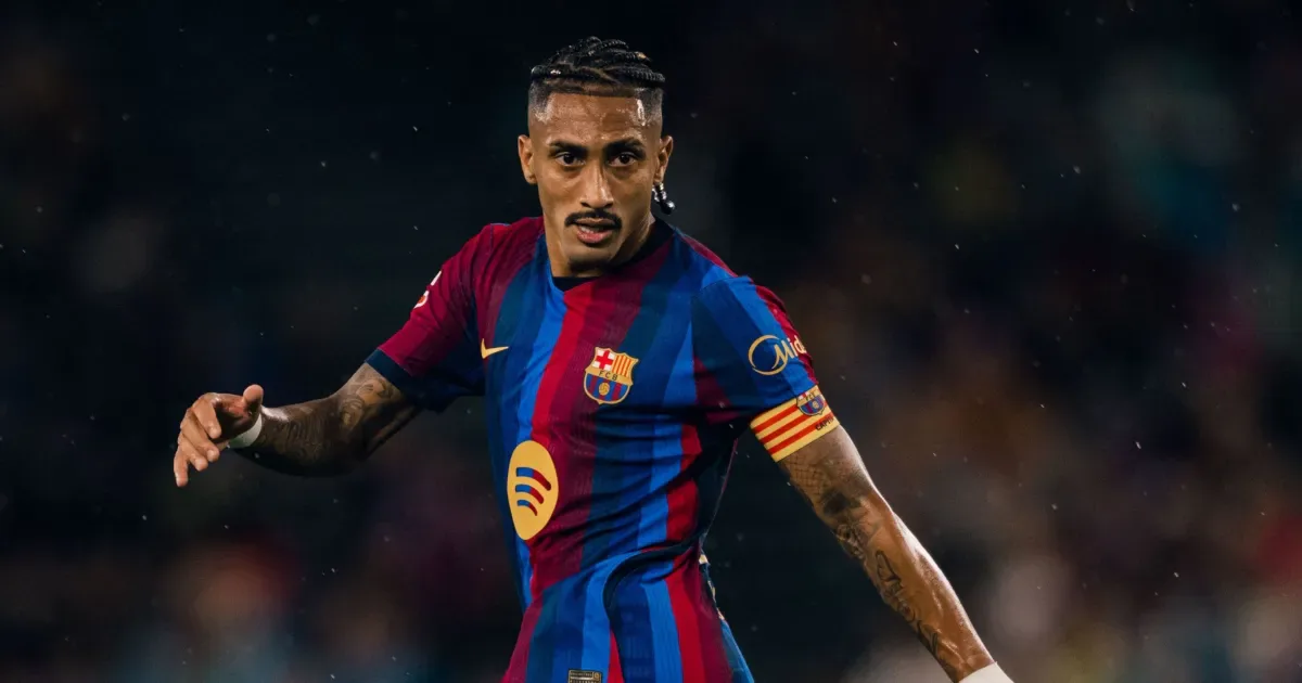 Jogador de camisa listrada em azul e grená, com braçadeira do Barcelona, olha em direção ao campo durante uma partida noturna