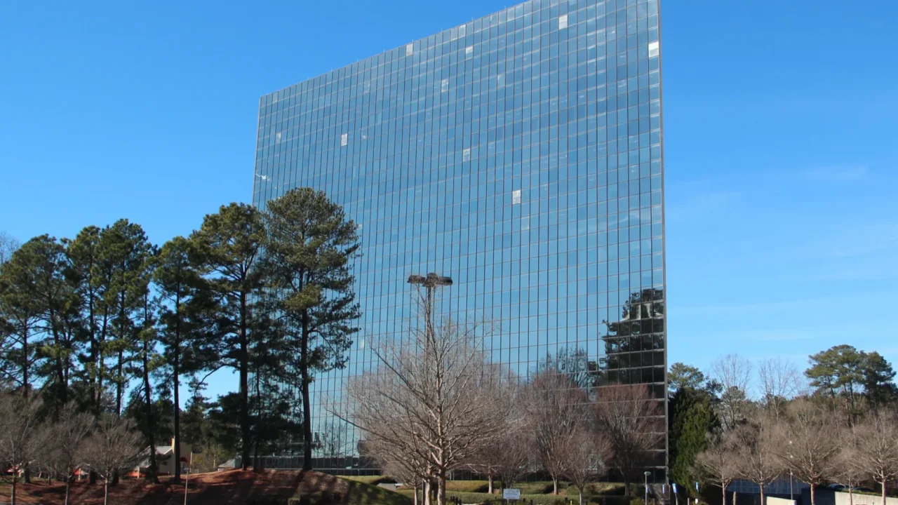 Torre de escritórios de 18 andares, toda de vidro espelhado, no número 1800 da Century Boulevard, em Chamblee, na Geórgia, com estacionamento vazio e árvores sem folhas em frente (foto de arquivo, janeiro de 2019)