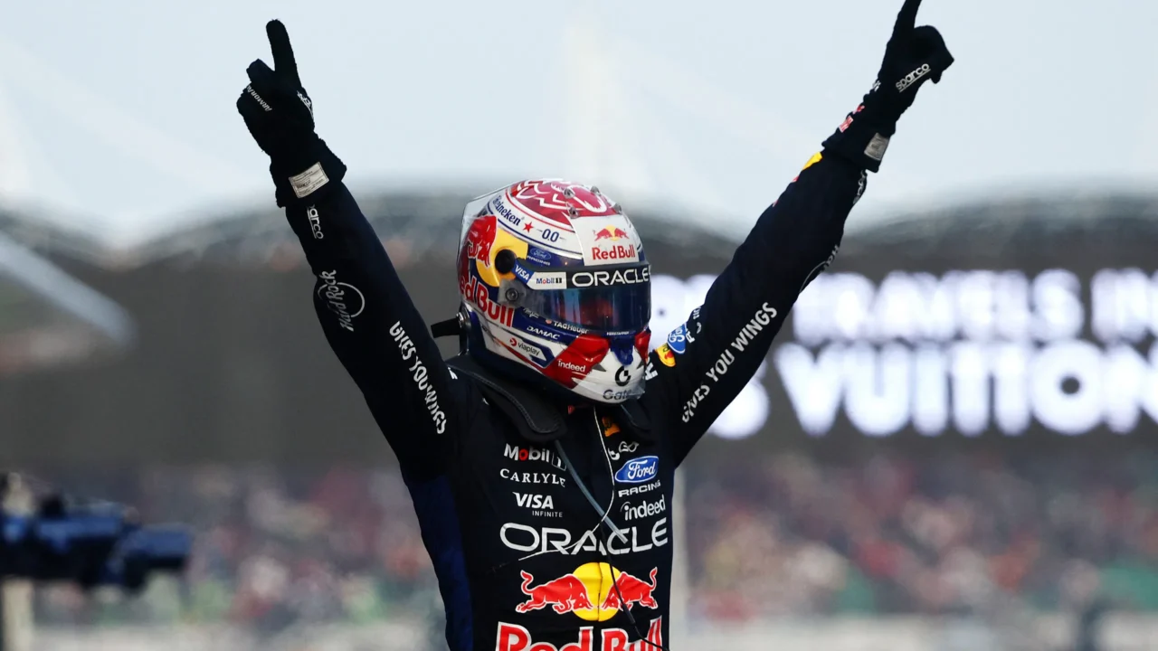 Piloto da Red Bull comemora com os braços levantados ao vencer corrida de Fórmula 1, usando capacete com patrocinadores e macacão da equipe com logos de Red Bull e Oracle