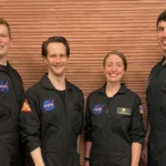 Os integrantes da tripulação da Missão 2 do CHAPEA (Crew Health and Performance Exploration Analog, Análogo de Exploração de Saúde e Desempenho da Tripulação) da NASA posam em seu espaço de trabalho depois de passarem um ano em seu habitat isolado e confinado no Centro Espacial Johnson da NASA, em