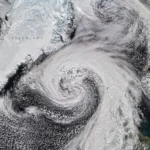 Nuvens de tempestade em espiral expansiva estão centradas perto do sul da Islândia. O sistema se estende pelo Atlântico Norte, da Groenlândia ao Reino Unido.