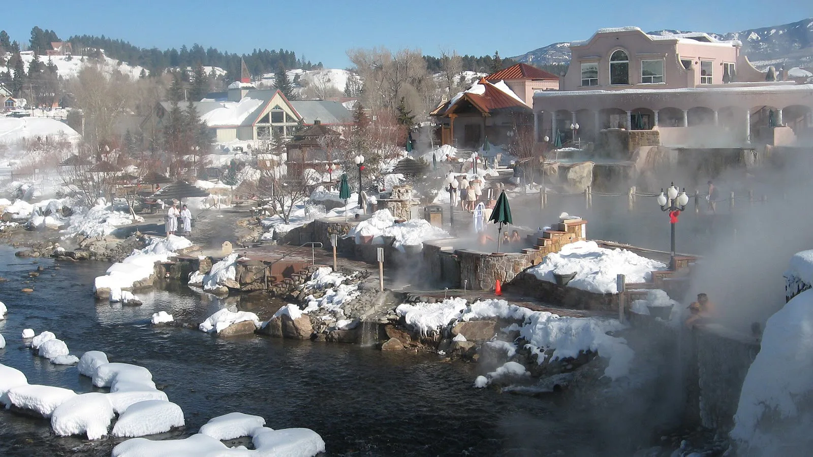 Piscinas de águas termais com vapor às margens do rio San Juan, em Pagosa Springs, com neve nas pedras e prédios ao fundo (imagem de arquivo)