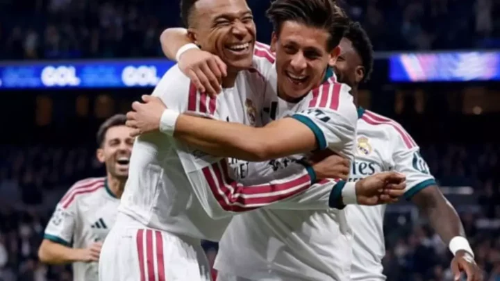 Jogadores do Real Madrid, de camisa branca, comemoram abraçados e sorrindo durante um jogo em estádio lotado