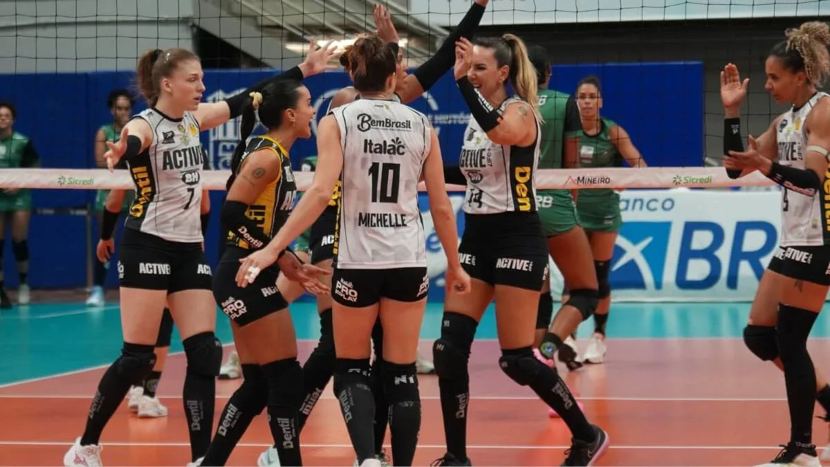 Jogadoras de vôlei com uniformes pretos e brancos comemoram um ponto em quadra, com a camisa 10 de Michelle de costas