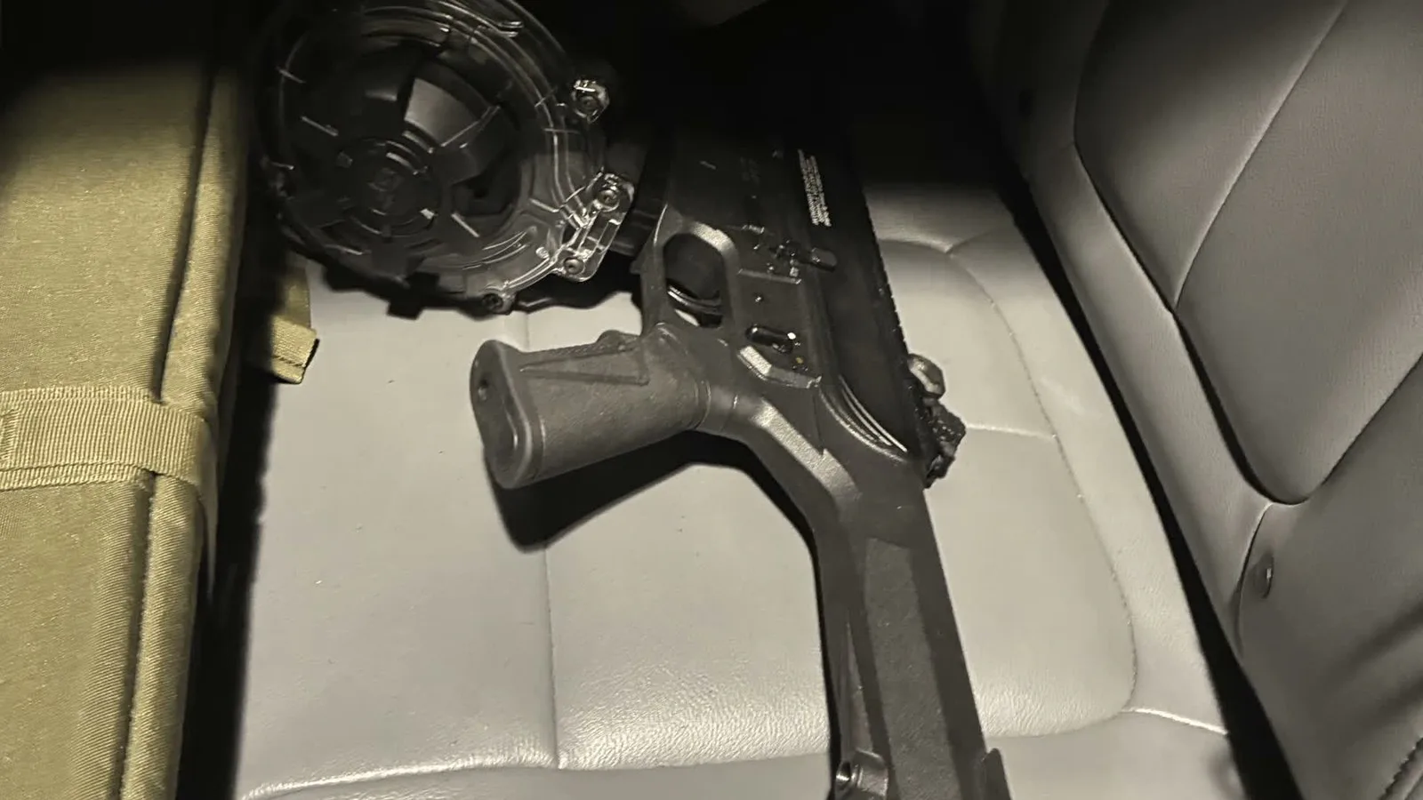 Arma com carregador de tambor sobre o banco de couro de um veículo, em imagem divulgada pelo xerife no relato das armas apreendidas