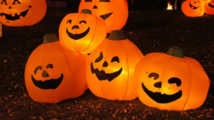 Abóboras infláveis de Halloween, iluminadas e com rostos sorridentes, enfeitam o jardim de uma casa à noite (imagem ilustrativa)
