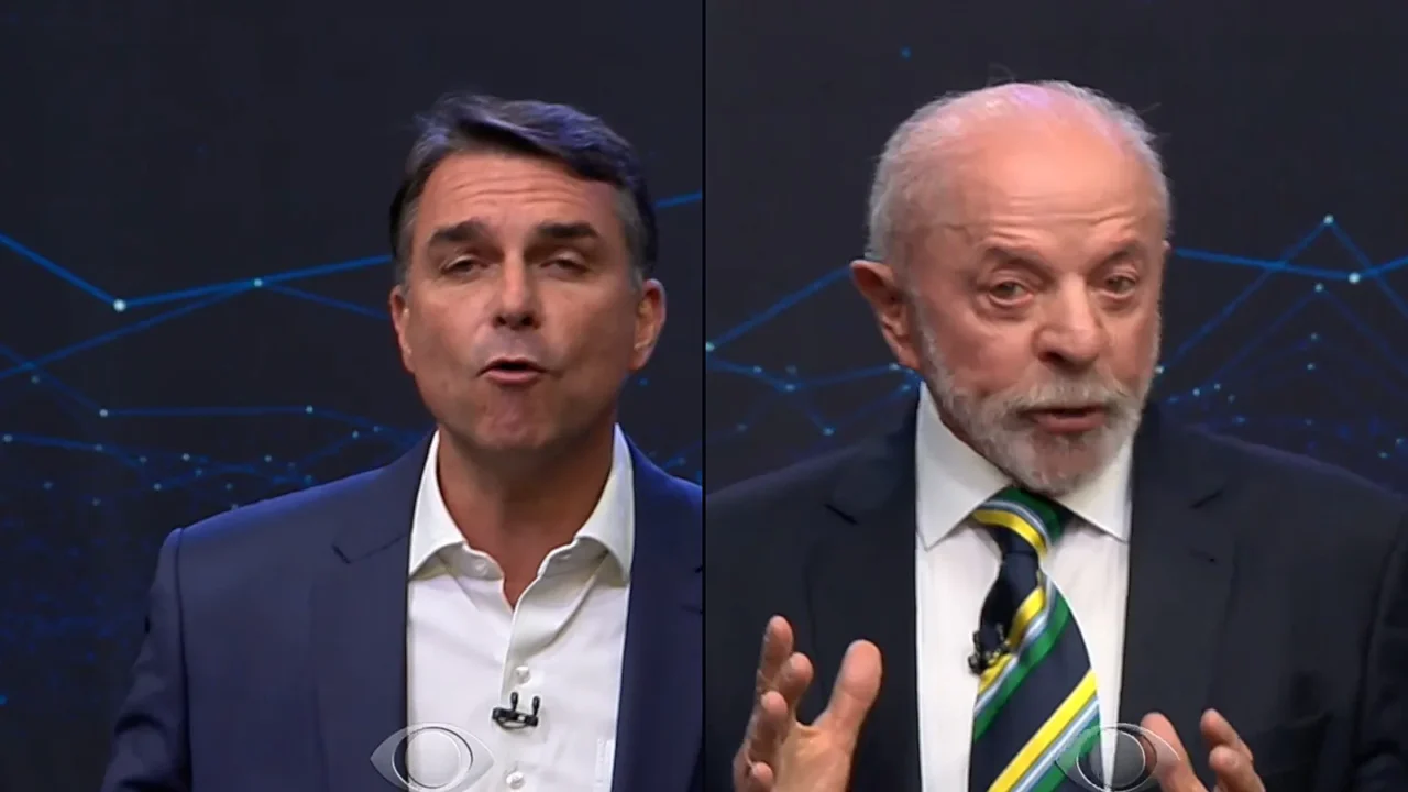 Montagem lado a lado: Flávio Bolsonaro à esquerda, de terno azul, e Lula à direita, de terno escuro e gravata verde e amarela, falando no debate
