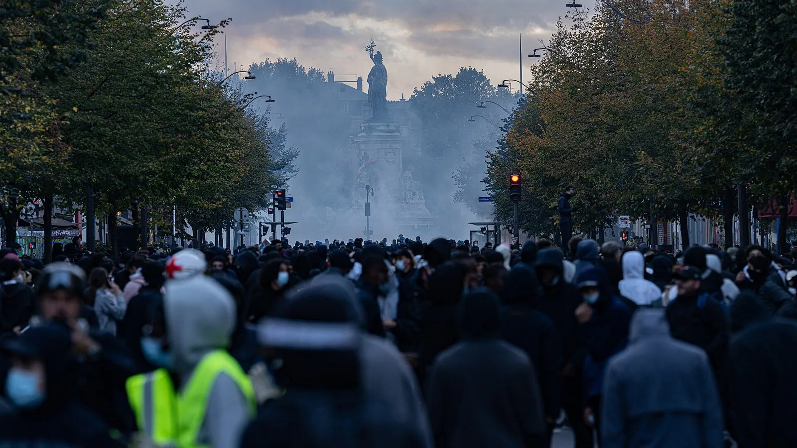 Multidão de encapuzados diante da Praça da República, em Paris, coberta de gás lacrimogêneo, em 17 de outubro de 2026
