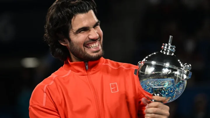 Tenista segura troféu de cristal enquanto sorri em comemoração de vitória em torneio ATP 500