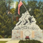 Cartão-postal antigo e colorido da estátua branca de Iwo Jima, com seis fuzileiros erguendo a bandeira americana, entre árvores na entrada da base de Quantico, na Virgínia (imagem de arquivo, anterior ao ataque)