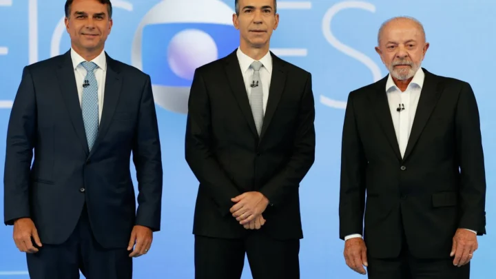 Flávio Bolsonaro, o mediador César Tralli e Lula, lado a lado no estúdio do debate da TV Globo, no Rio de Janeiro, em 23 de outubro de 2026