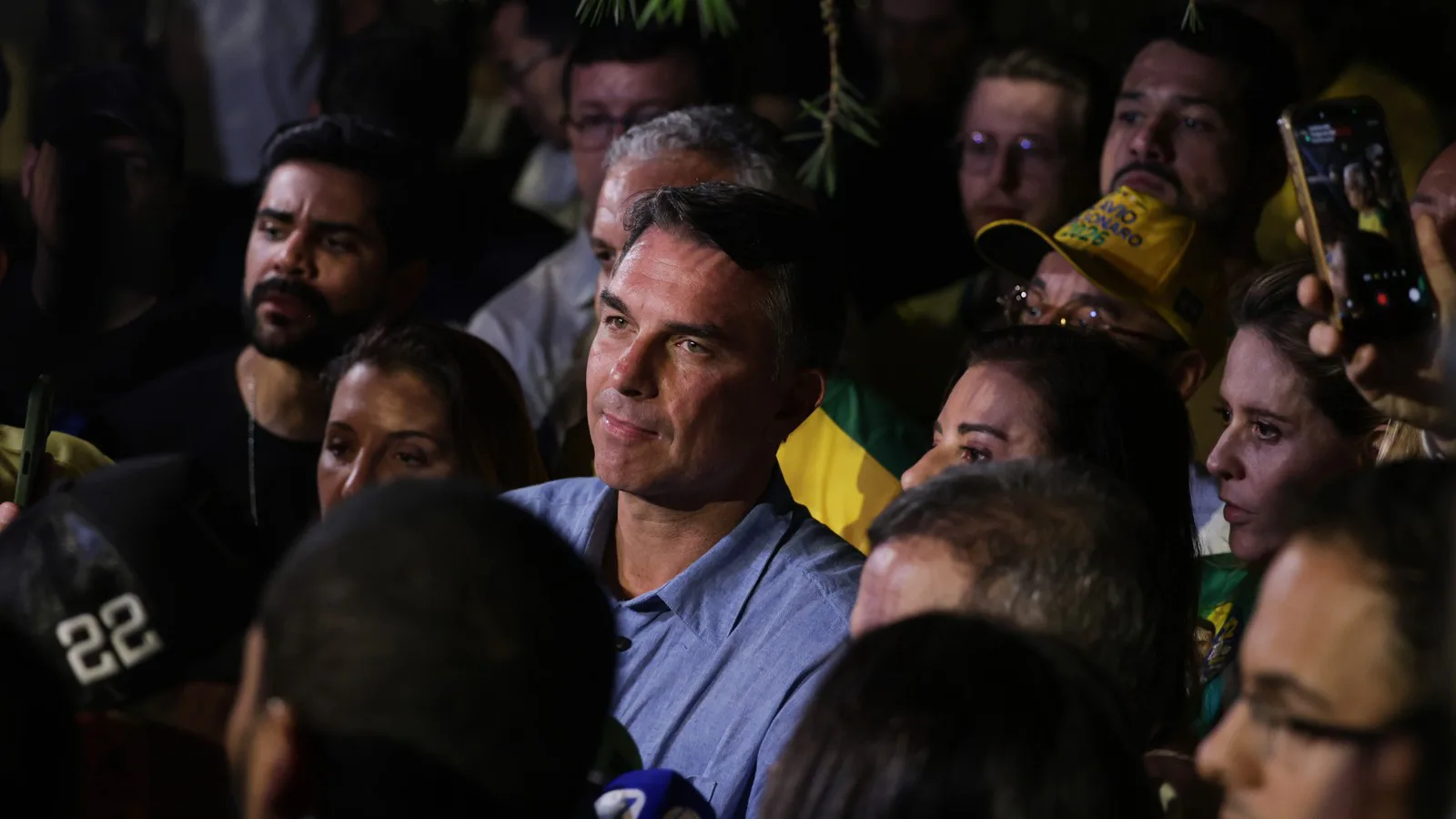 Flávio Bolsonaro, cercado de pessoas e microfones, fala com jornalistas em Brasília na noite de 4 de outubro de 2026