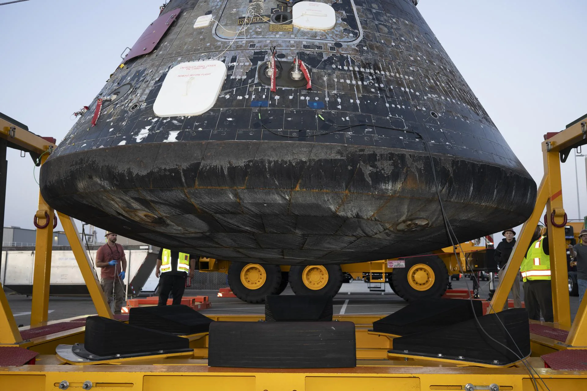 O módulo de tripulação Orion da Artemis II após ser descarregado do convés de embarque do USS John P. Murtha na Base Naval de San Diego e içado do Conjunto de Berço de Recuperação da Orion em 18 de abril de 2026. A área cinza, vista na borda onde o escudo térmico da espaçonave encontra a casca traseira (backshell), é resultado das operações de recuperação.
