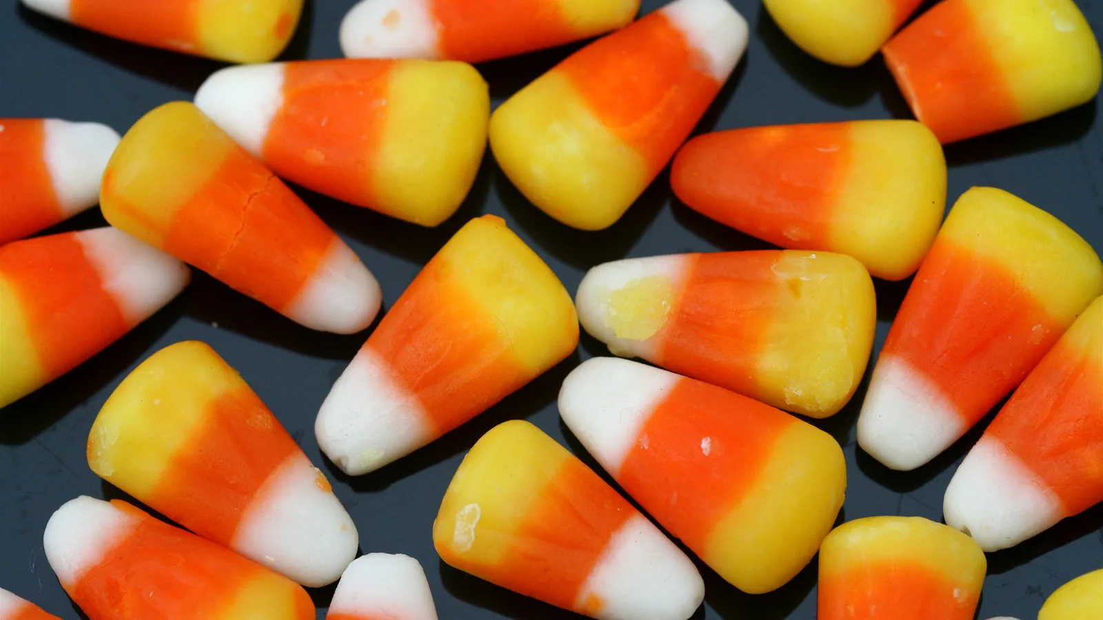 Foto de arquivo de balas de milho (candy corn) espalhadas sobre uma superfície escura, em close