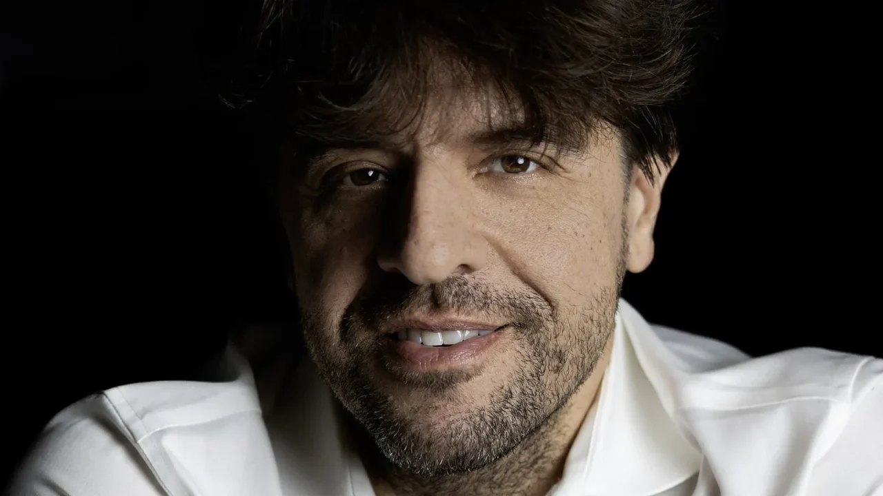 Retrato do neurocientista Karl Deisseroth, de camisa branca, sorrindo sobre fundo escuro