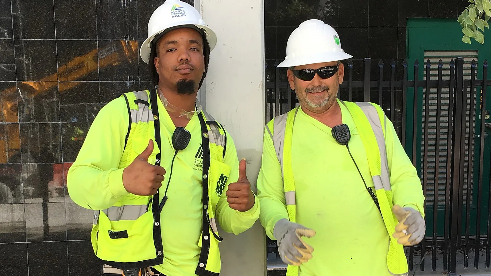 Dois operários de construção com capacete e colete refletivo posam em obra em Miami, na Flórida