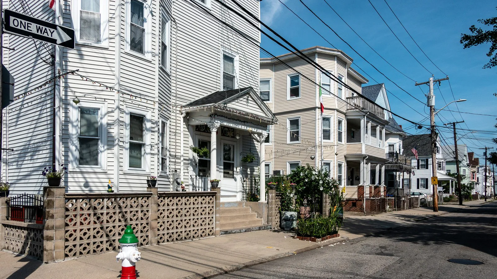 Foto de arquivo de uma rua residencial do bairro Federal Hill, em Providence, com casas de madeira de vários andares, fios de poste e um hidrante pintado de verde, branco e vermelho