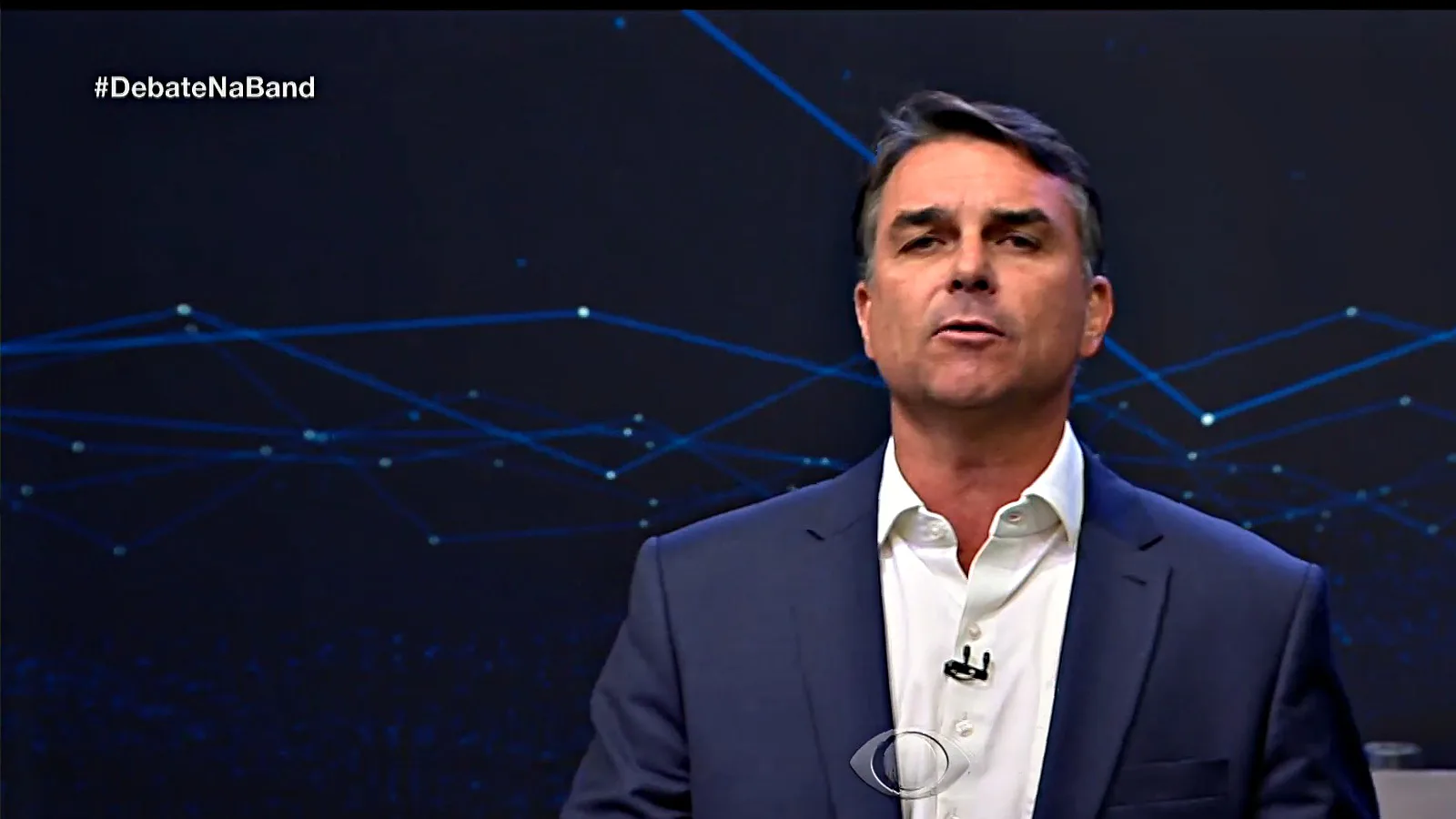 Flávio Bolsonaro, de terno azul e camisa branca, responde à pergunta sobre segurança pública