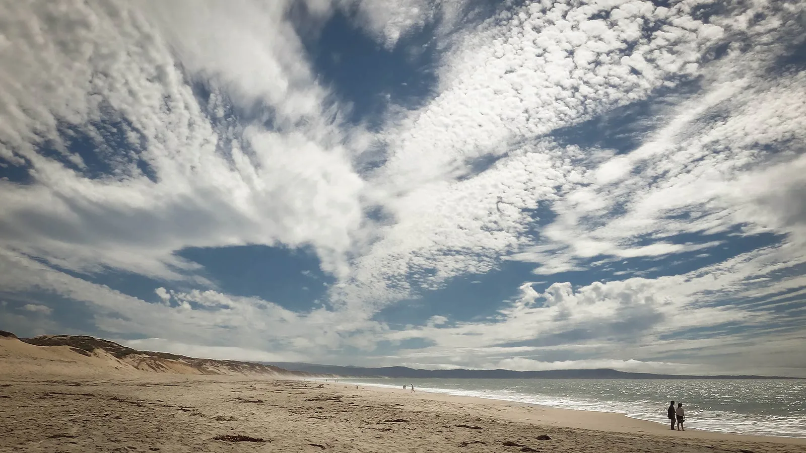 Faixa de areia e dunas de Marina State Beach, na Baía de Monterey, sob céu com nuvens