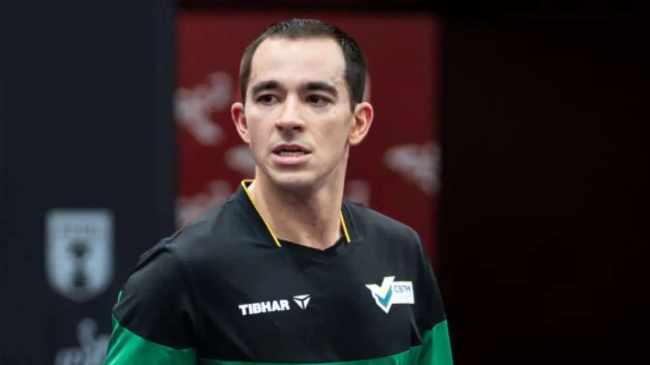 Atleta de camisa preta e verde, com patrocínio Tibhar e logo da CBTM, olha para o lado durante evento esportivo