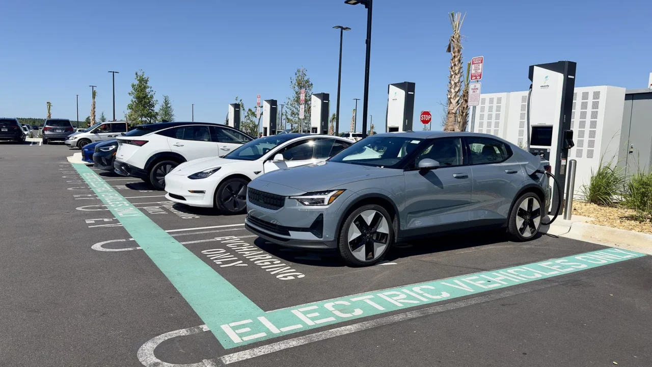 Carros elétricos estacionados em vagas exclusivas, ligados a carregadores, no estacionamento de uma loja em Clermont, na Flórida
