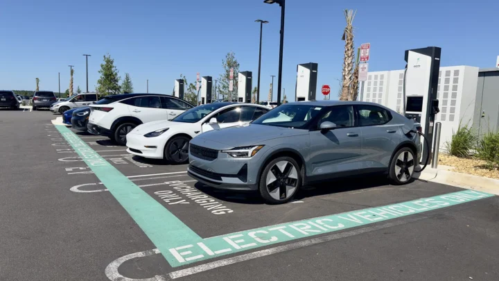 Carros elétricos estacionados em vagas exclusivas, ligados a carregadores, no estacionamento de uma loja em Clermont, na Flórida