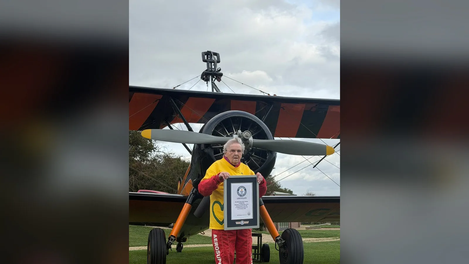 Helga Duffy segura o certificado do Guinness World Records em frente ao biplano, depois do pouso