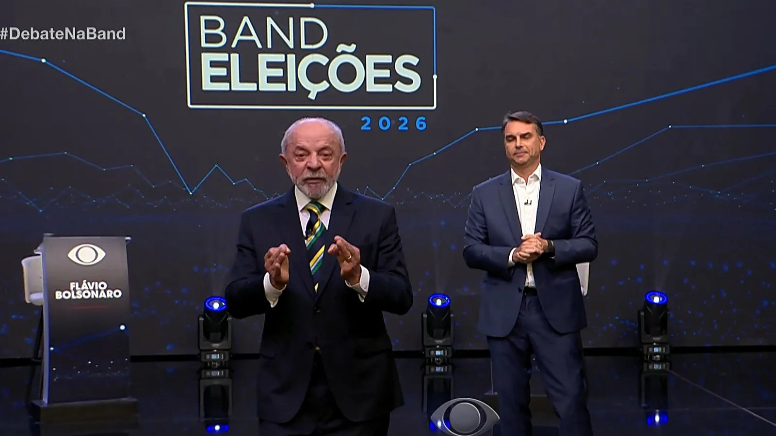 Lula e Flávio Bolsonaro no palco do debate, sob o painel "Band Eleições 2026"