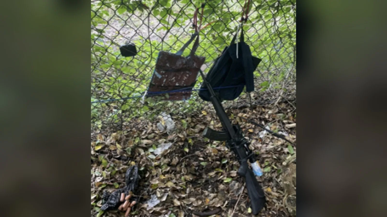 Mochila pendurada numa cerca e fuzil no chão, entre folhas secas, no local onde Ryan Routh se escondia