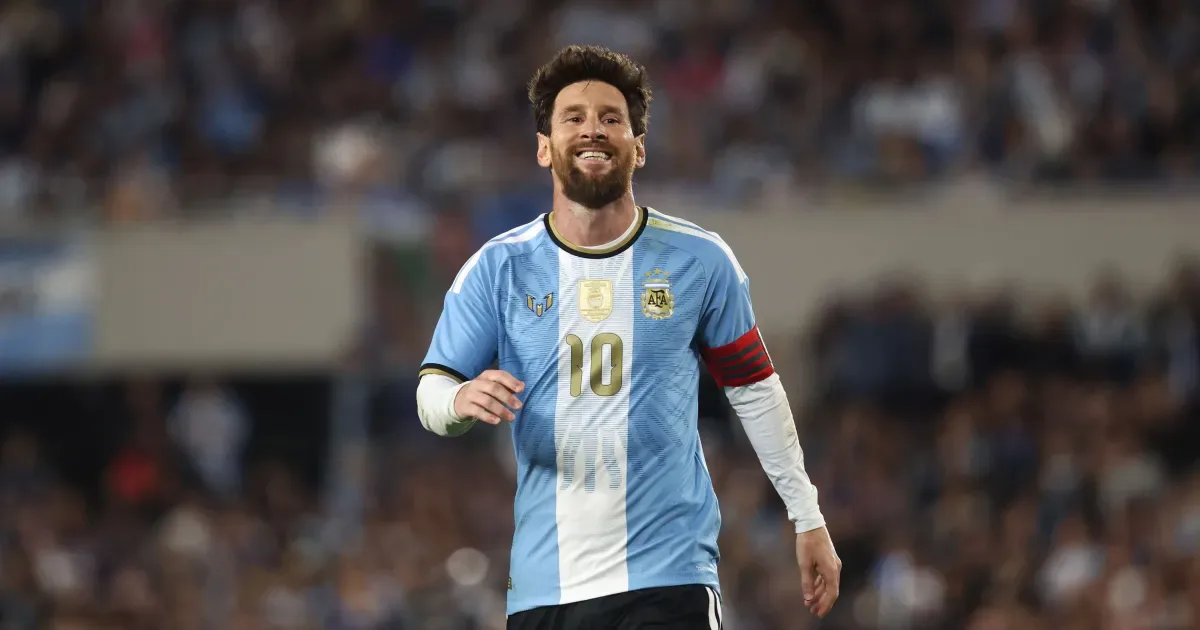 Jogador com camisa listrada azul e branca número 10 corre em campo durante partida de futebol com público ao fundo