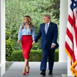 Melania Trump e Donald Trump caminham de mãos dadas pela colunata da Casa Branca, ao lado de uma bandeira americana, a caminho de um evento da iniciativa Fostering the Future com a IndyCar, em 20 de agosto de 2026 (imagem de arquivo)