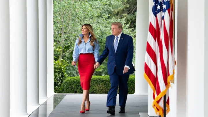Melania Trump e Donald Trump caminham de mãos dadas pela colunata da Casa Branca, ao lado de uma bandeira americana, a caminho de um evento da iniciativa Fostering the Future com a IndyCar, em 20 de agosto de 2026 (imagem de arquivo)