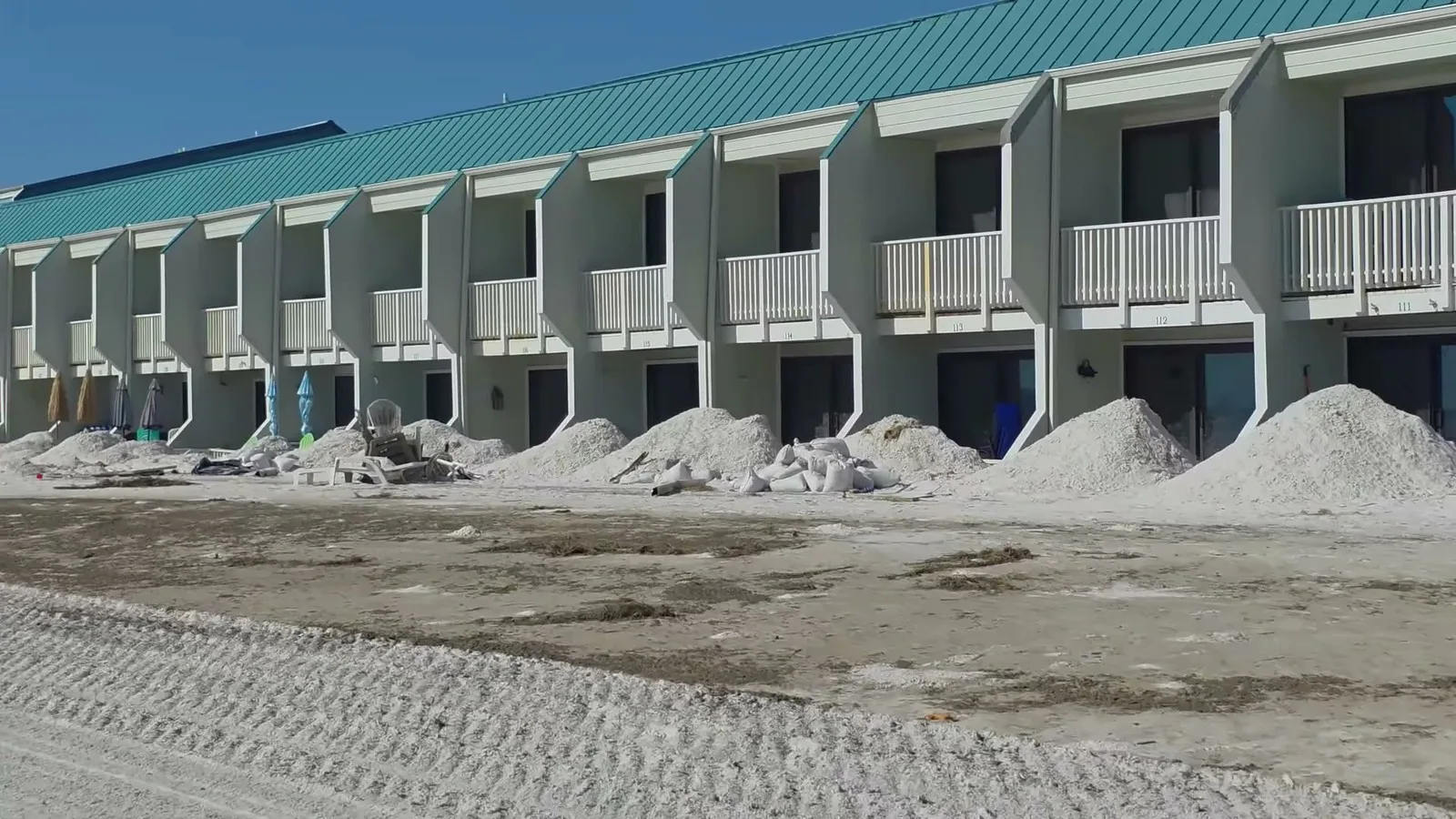 Montes de areia acumulados diante de um prédio de apartamentos à beira-mar depois da tempestade