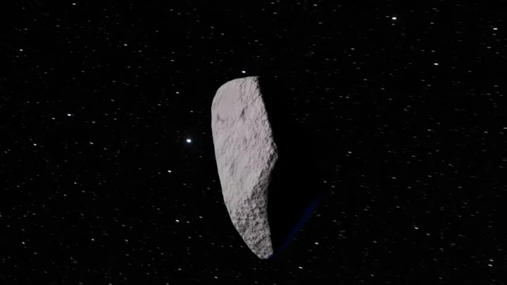Animação mostra um asteroide alongado e acinzentado contra um fundo de estrelas