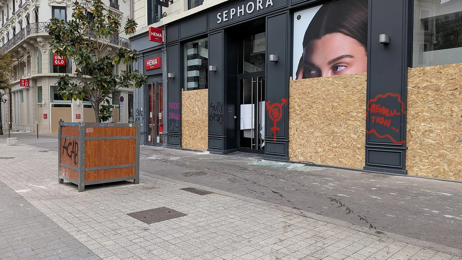 Vitrines de lojas cobertas com tapumes de madeira na Praça da República, em Lyon, depois dos atos de 17 de outubro de 2026