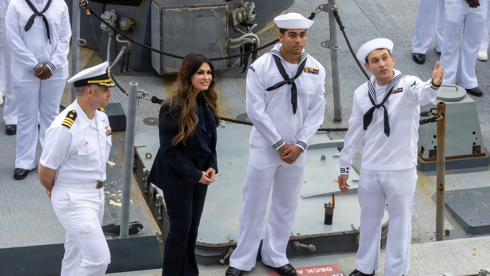 Kimberly Guilfoyle, de terninho escuro, conversa com marinheiros de uniforme branco no convés do destróier USS Oscar Austin, na baía de Souda, na Grécia, em maio de 2026
