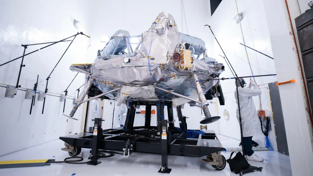 Microfones são dispostos ao redor do Griffin-1 em 12 de agosto durante o teste acústico que imita o estrondo intenso do lançamento. Buzinas gigantes alimentadas por gás nitrogênio comprimido bombardeiam a espaçonave com até 153 decibéis dentro de uma câmara acústica selada no JPL.