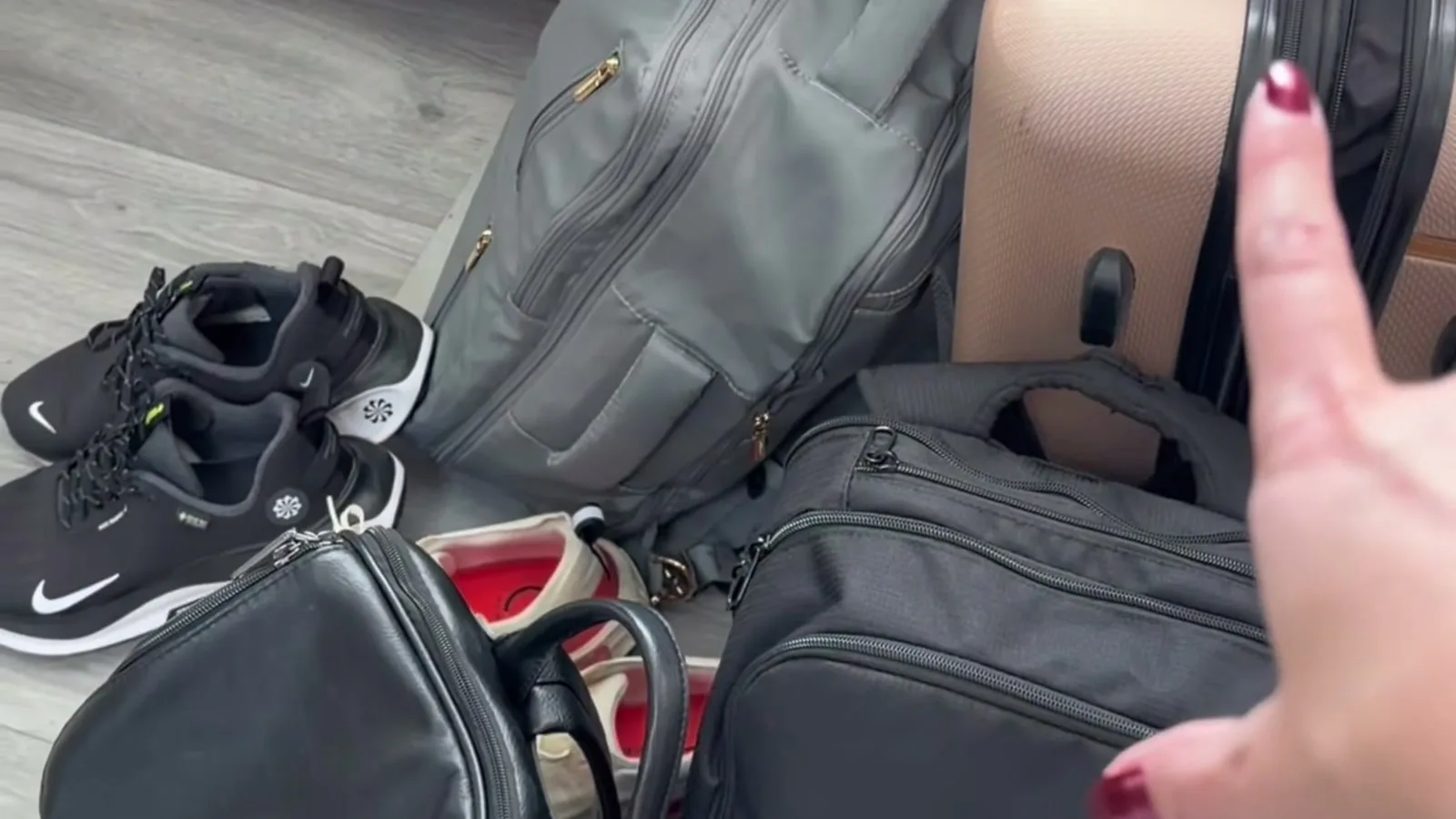 Mochilas, mala de rodinhas e tênis separados no chão de um quarto para a saída de casa